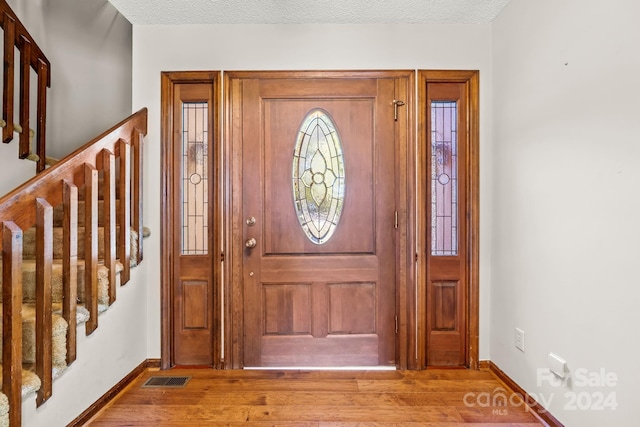 foyer entrance with a textured ceiling and light hardwood / wood-style flooring