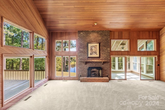 unfurnished living room with a wealth of natural light, wooden walls, a fireplace, and a water view