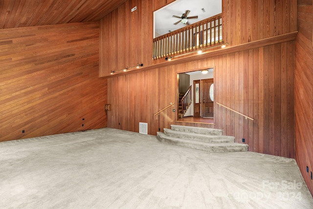 staircase featuring wood walls, high vaulted ceiling, and ceiling fan