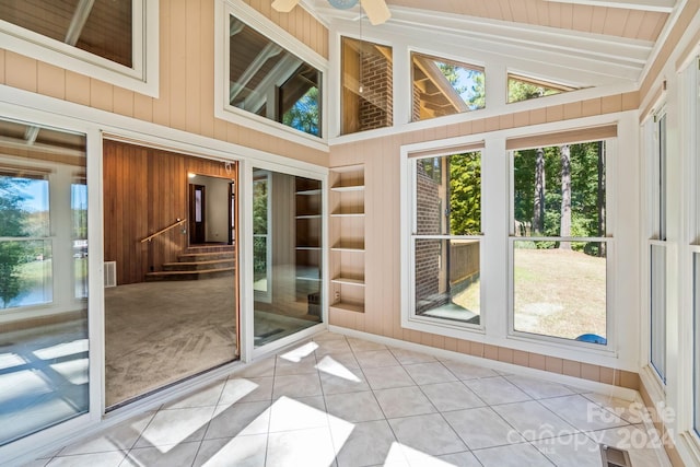 unfurnished sunroom featuring ceiling fan, lofted ceiling, and a wealth of natural light