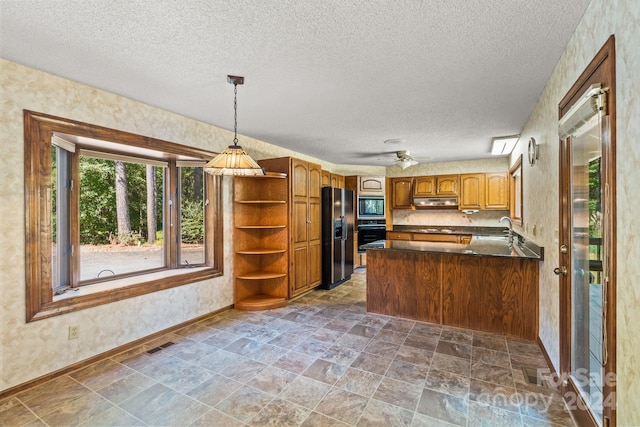 kitchen featuring kitchen peninsula, ceiling fan, a textured ceiling, stainless steel appliances, and sink