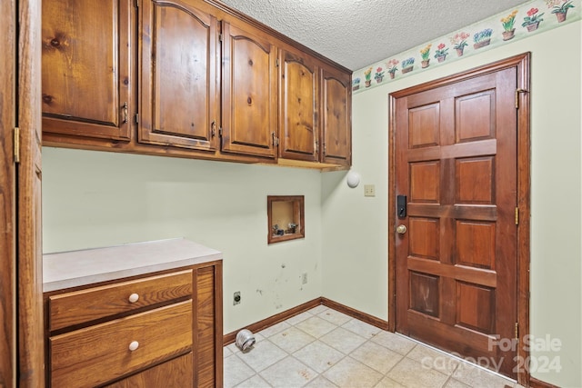 clothes washing area featuring hookup for a washing machine, a textured ceiling, and cabinets