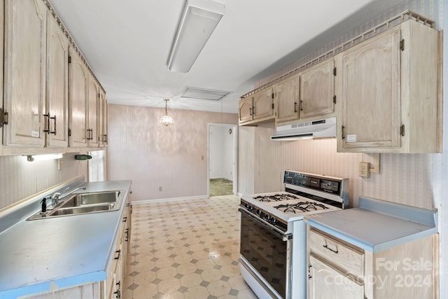 kitchen with sink, light brown cabinets, decorative light fixtures, and white gas range