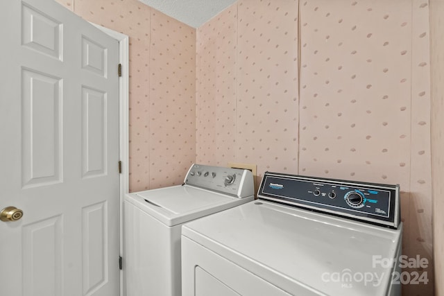 clothes washing area with washer and clothes dryer and a textured ceiling