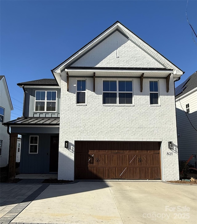 view of front of home with a garage, metal roof, a standing seam roof, and concrete driveway