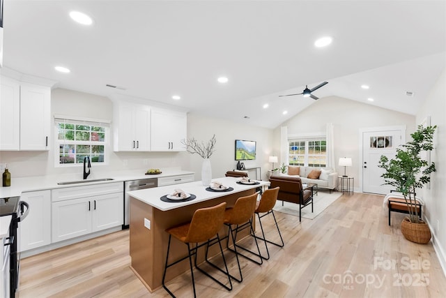 kitchen featuring ceiling fan, sink, a kitchen island, a kitchen breakfast bar, and white cabinets