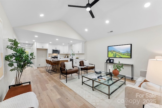 living room featuring high vaulted ceiling, light hardwood / wood-style flooring, ceiling fan, and sink