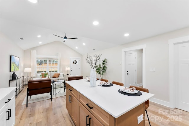 kitchen with ceiling fan, a center island, light hardwood / wood-style floors, and lofted ceiling