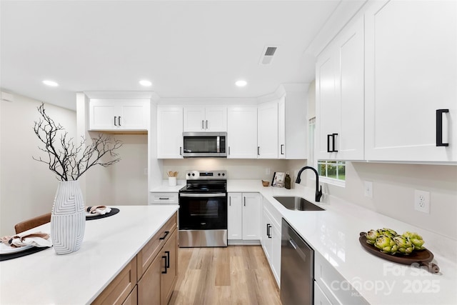 kitchen featuring sink, white cabinets, light wood-type flooring, and appliances with stainless steel finishes