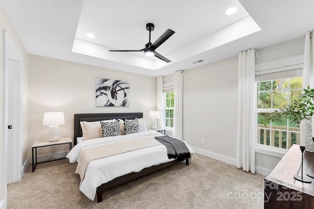 bedroom featuring a tray ceiling, ceiling fan, and light carpet