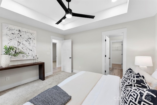 carpeted bedroom with a raised ceiling and ceiling fan