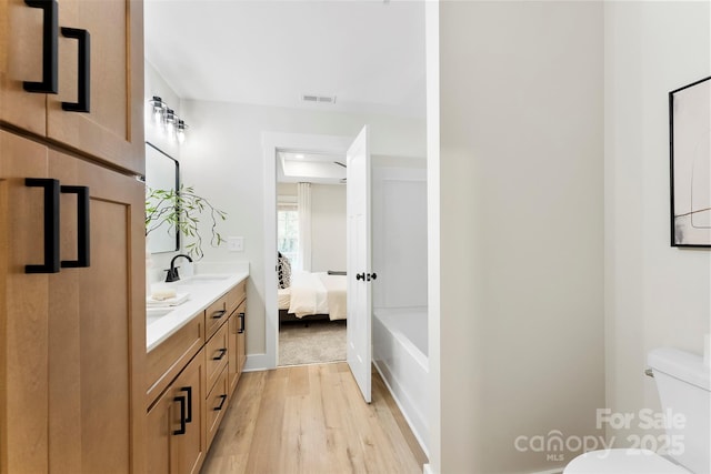 bathroom with hardwood / wood-style floors, vanity, and toilet