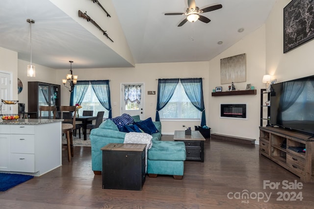 living room featuring a healthy amount of sunlight, vaulted ceiling, ceiling fan with notable chandelier, and dark hardwood / wood-style flooring