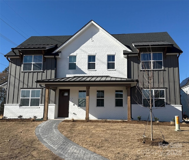 modern farmhouse style home featuring metal roof, brick siding, a shingled roof, board and batten siding, and a standing seam roof