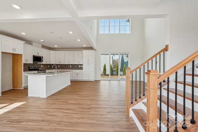 809 Terra Dr, Tega Cay, SC 29708 - kitchen with light wood finished floors, white cabinetry, stainless steel appliances, and an island with sink