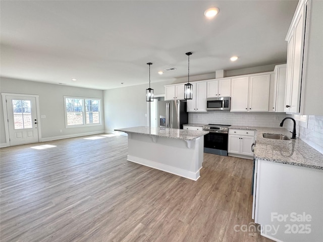 kitchen with a kitchen island, sink, white cabinets, and stainless steel appliances