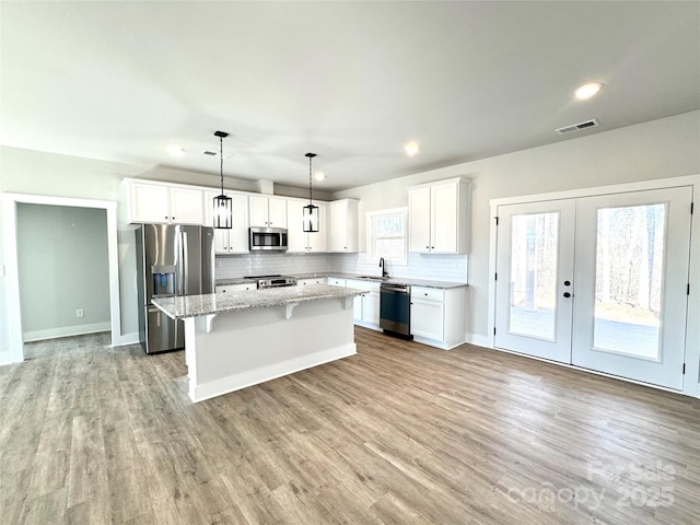 kitchen featuring appliances with stainless steel finishes, sink, decorative light fixtures, white cabinetry, and a kitchen island