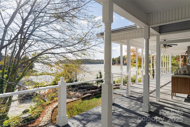 wooden terrace with a water view and ceiling fan