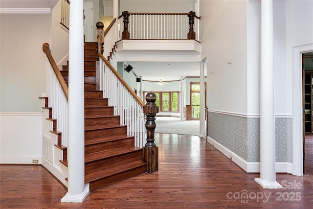 staircase featuring decorative columns, crown molding, wood-type flooring, and ceiling fan