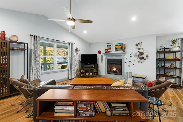 living room featuring ceiling fan, lofted ceiling, and light wood-type flooring