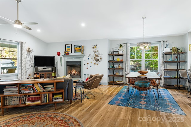 dining area featuring lofted ceiling, ceiling fan with notable chandelier, and light wood-type flooring