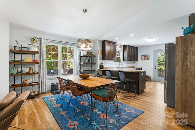 dining space featuring sink, vaulted ceiling, and light hardwood / wood-style floors