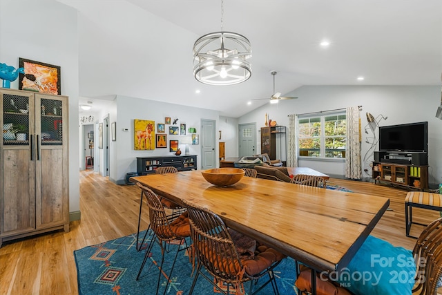 dining space featuring lofted ceiling, ceiling fan with notable chandelier, and light wood-type flooring