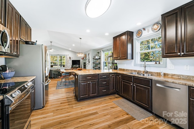 kitchen with sink, appliances with stainless steel finishes, hanging light fixtures, vaulted ceiling, and kitchen peninsula