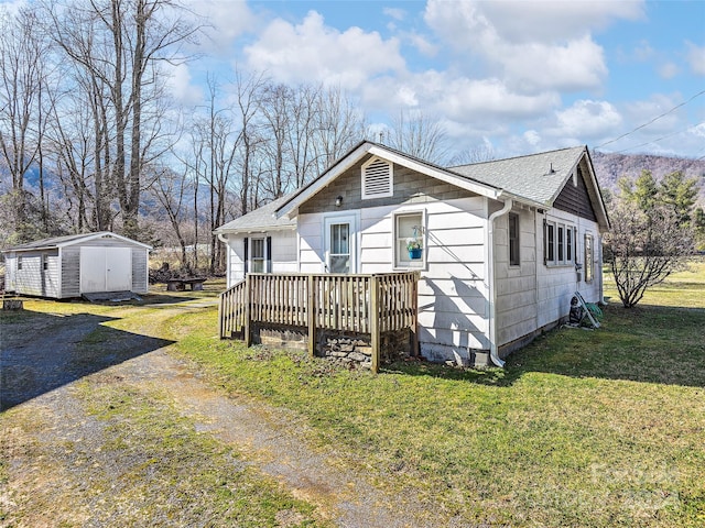 view of front of house with a storage shed, a front yard, and a deck