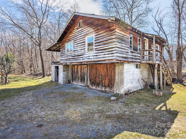 view of property exterior with a wooden deck, a lawn, and a garage