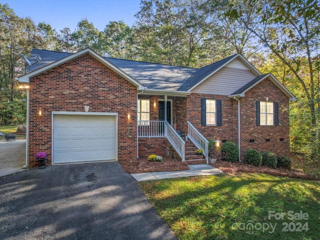 view of front of house featuring covered porch, a garage, and a front yard