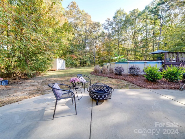 view of patio featuring an outdoor fire pit, a pool side deck, and a storage shed