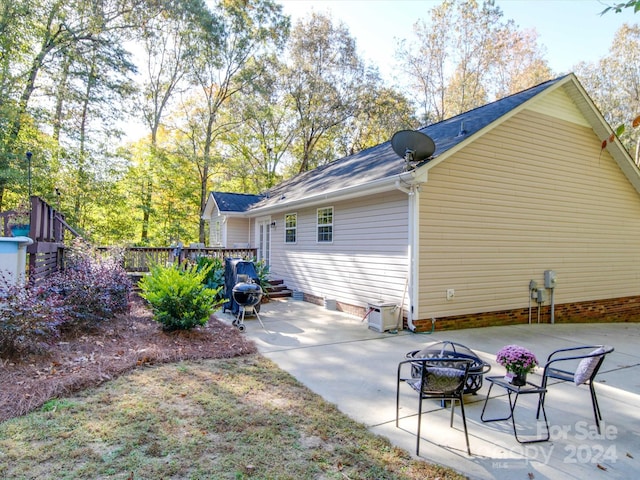 rear view of house featuring a wooden deck and a patio