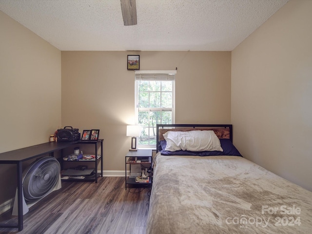 bedroom with a textured ceiling, dark wood-type flooring, and ceiling fan