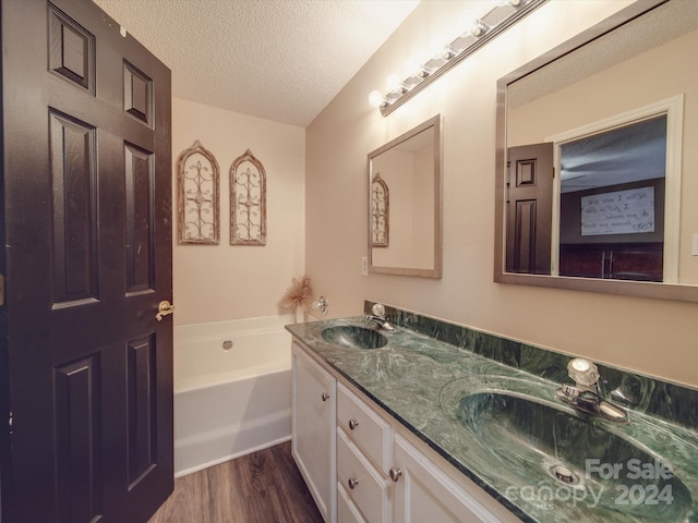 bathroom featuring vanity, a tub, a textured ceiling, and hardwood / wood-style floors