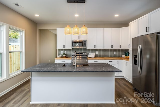 kitchen with a center island with sink, white cabinets, stainless steel appliances, and dark hardwood / wood-style floors