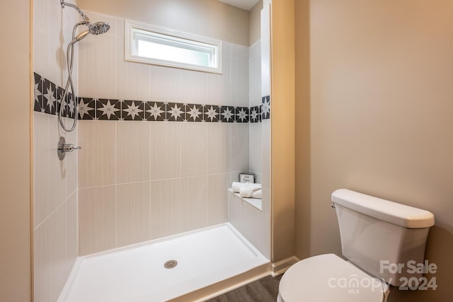 bathroom featuring tiled shower and toilet