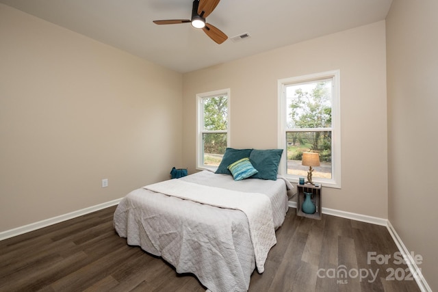 bedroom with multiple windows, dark hardwood / wood-style floors, and ceiling fan