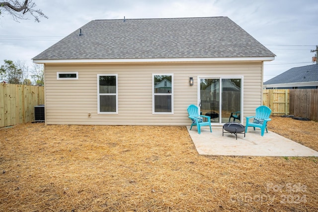 rear view of property featuring central air condition unit, a patio area, and an outdoor fire pit