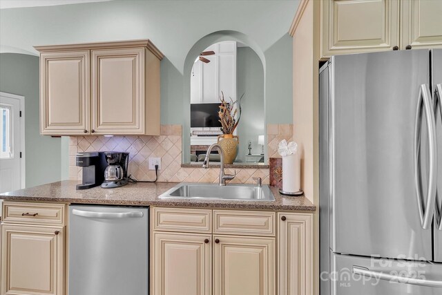 kitchen with tasteful backsplash, appliances with stainless steel finishes, sink, and cream cabinets