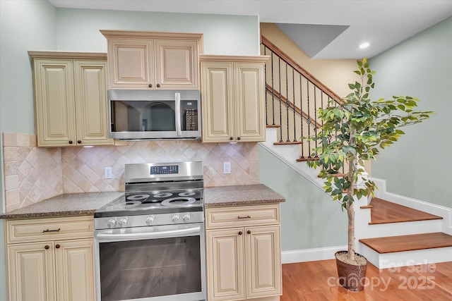 kitchen with tasteful backsplash, light hardwood / wood-style floors, stainless steel appliances, and cream cabinetry