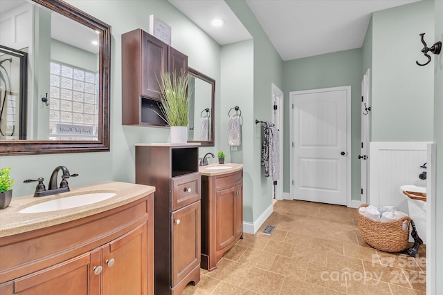 full bath with two vanities, baseboards, and a sink