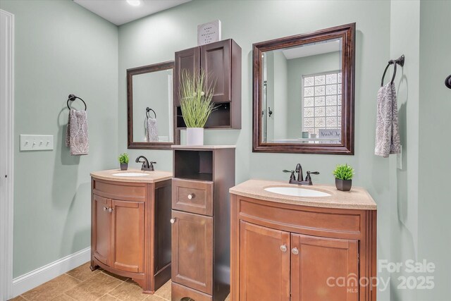 bathroom with two vanities, baseboards, and a sink