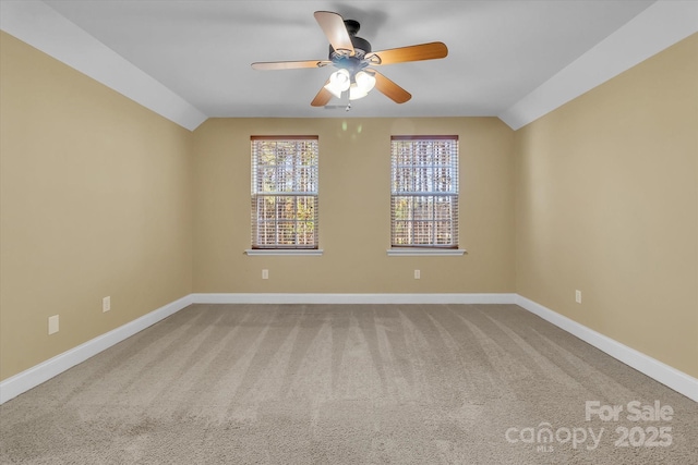 carpeted spare room featuring vaulted ceiling and ceiling fan