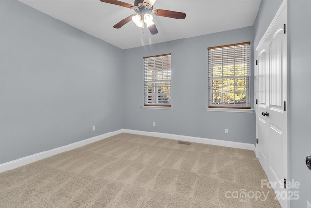 spare room featuring light carpet, visible vents, baseboards, and a ceiling fan