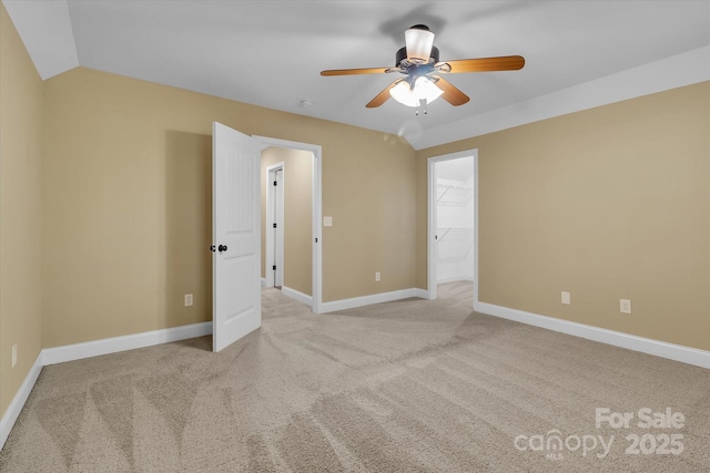 carpeted spare room featuring baseboards, lofted ceiling, and ceiling fan