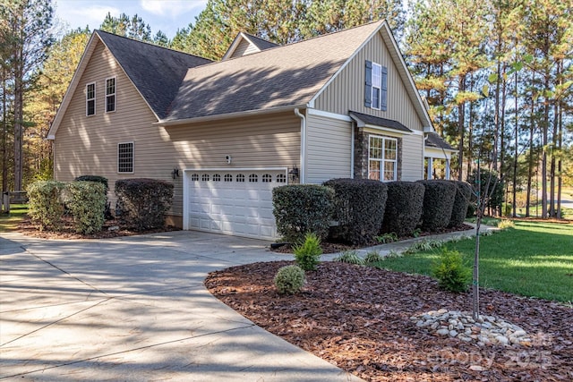 view of side of home with concrete driveway, an attached garage, a yard, and a shingled roof