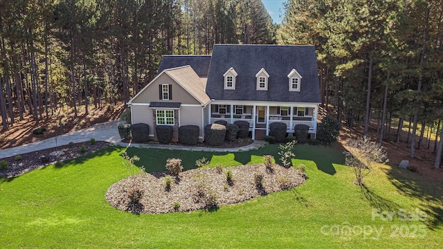 new england style home featuring roof with shingles, a front lawn, and a sunroom