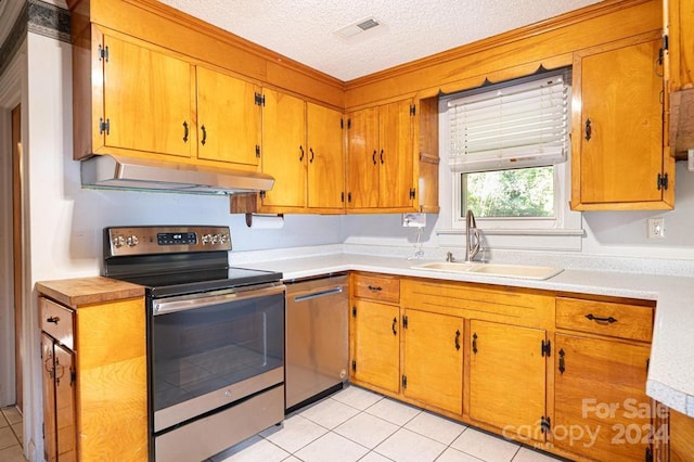 kitchen featuring light tile patterned flooring, appliances with stainless steel finishes, sink, and a textured ceiling