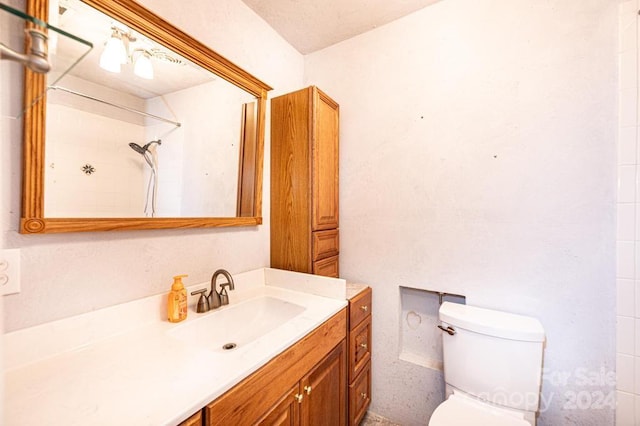 bathroom featuring vanity, toilet, a textured ceiling, and tiled shower